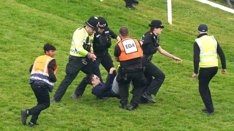 Newman is removed from the track shortly before the Derby field head for the finish