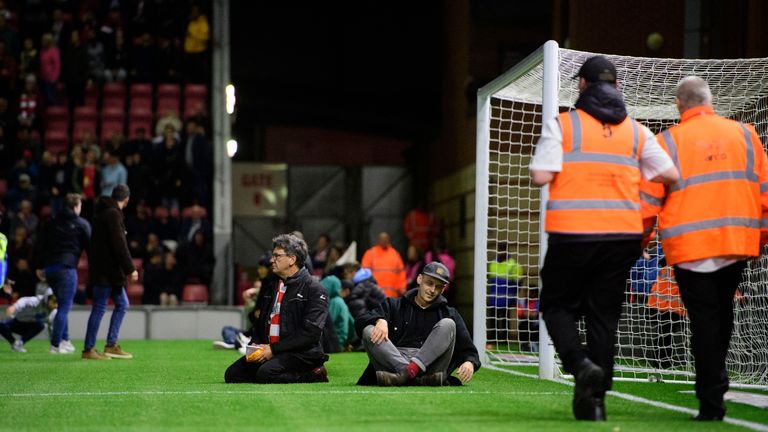 Leyton Orient fans sit on the pitch to try and get the game stopped against Lincoln                                              