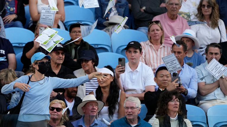 A woman throws "free Palestine" leaflets onto Margaret Court Arena during the fourth round match between Alexander Zverev of Germany and Cameron Norrie of Britain at the Australian Open tennis championships at Melbourne Park, Melbourne, Australia, Monday, Jan. 22, 2024. (AP Photo/Alessandra Tarantino)