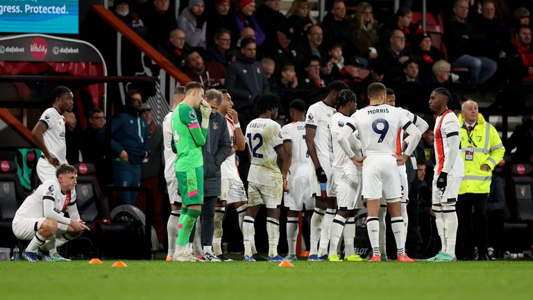 Luton Town's players wait on the sideline as team-mate Tom Lockyer (not pictured) receives treatment after collapsing on the pitch