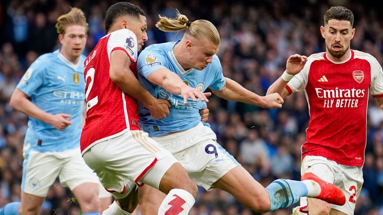 Erling Haaland attempts to shoot despite pressure from William Saliba