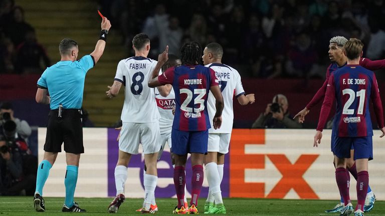 Referee Istvan Kovacs, left, shows a red card to Ronald Araujo