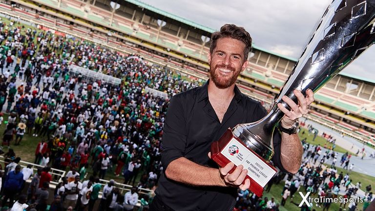 Nairobi, Kenya. 25 Jun 2023.  Johnathan MCKINSTRY (Head Coach, Gor Mahia) with the 2022-23 KPL league winners trophy. In the background, Gor Mahia fans who had flooded onto to the pitch following the final whistle Nairobi City Stars v Gor Mahia, Kenyan Premier League.  Gor Mahia won 4-1, becoming Champions of the Kenyan Premier League. Kasarani Stadium. Credit: XtraTimeSports (Darren McKinstry)